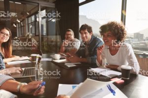 4 people engaged in conversation around a conference table