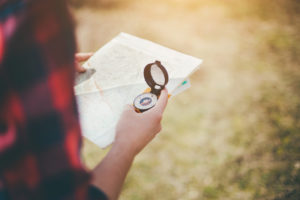 A person is holding a compass while looking at a map.